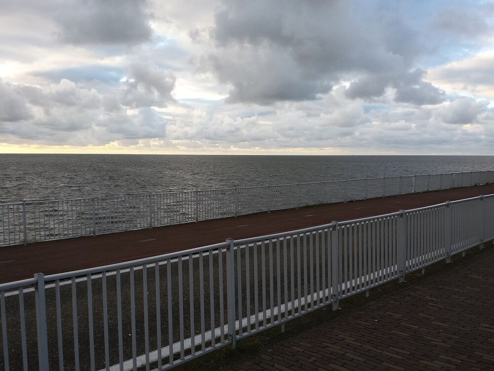 Fietspad met wit hekwerk op de dijk bij Den Oever met uitzicht over het water